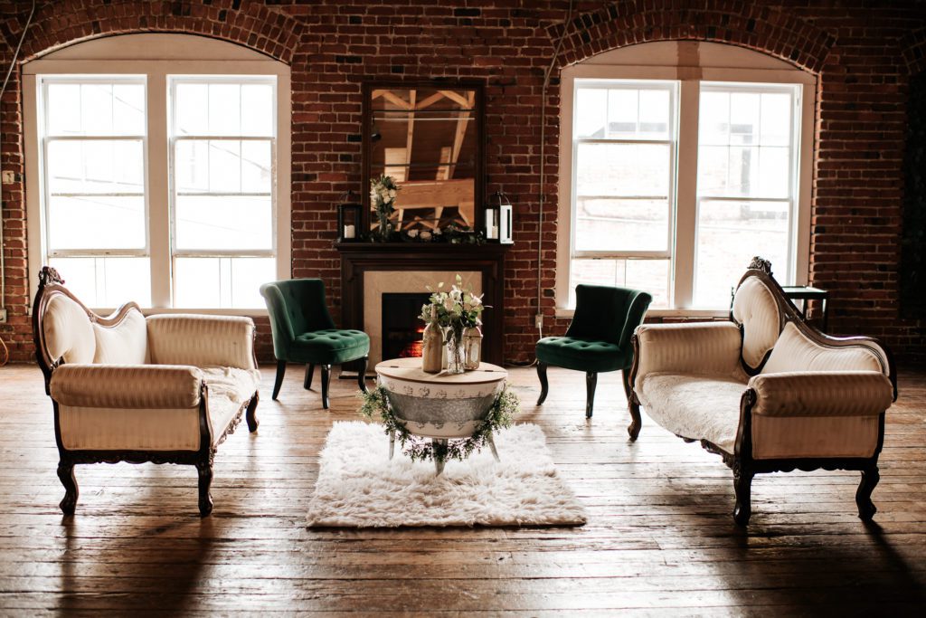 Vintage furniture wedding set up in a brick room with a electric fireplace