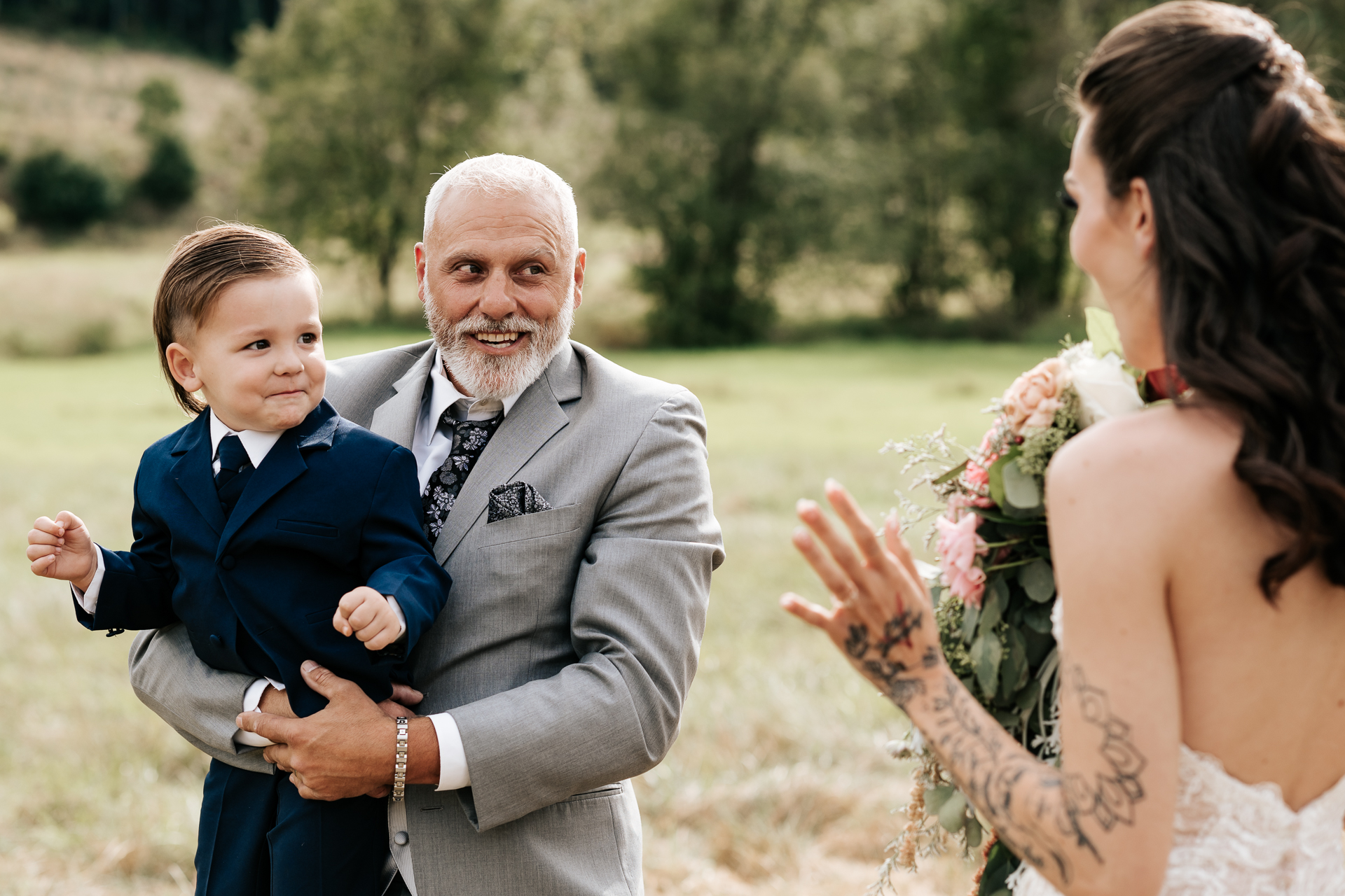 Father of the bride and son of the bride see her for the first time in her wedding dress