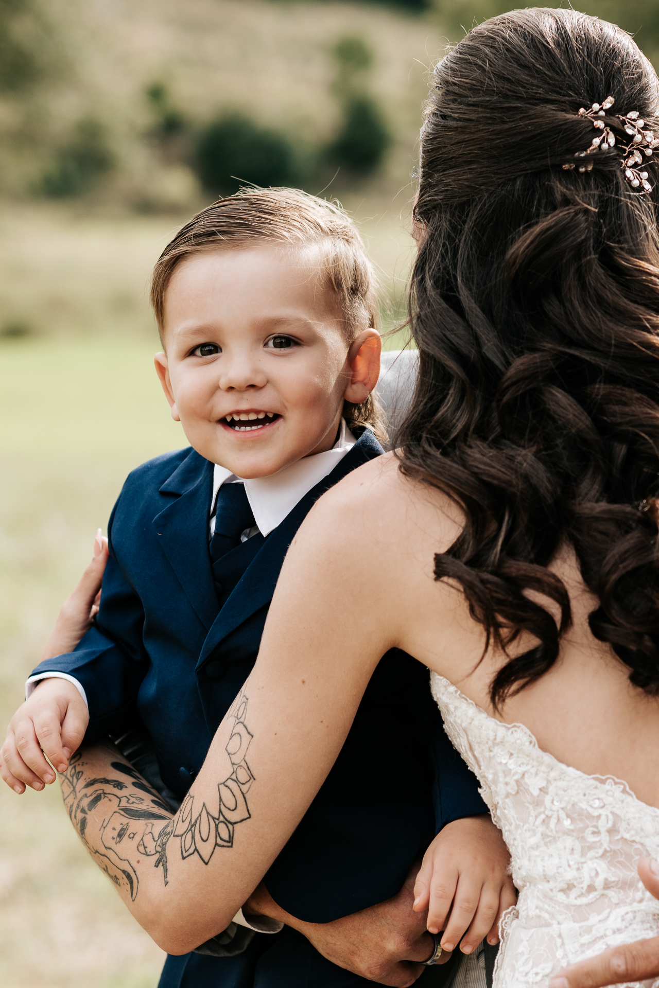 Son of the bride smiling after seeing his mom for the first time in her boho wedding dress
