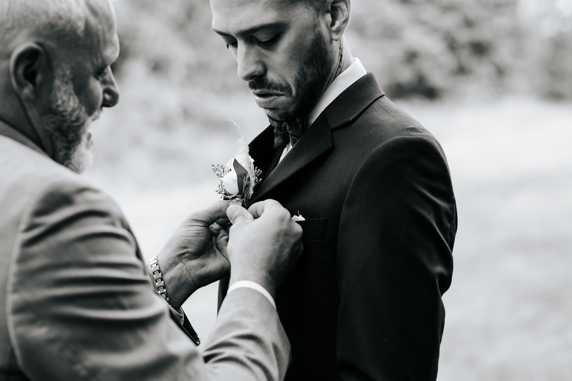 Black and White photo Father of the Bride pins Groom's Boutonniere on 