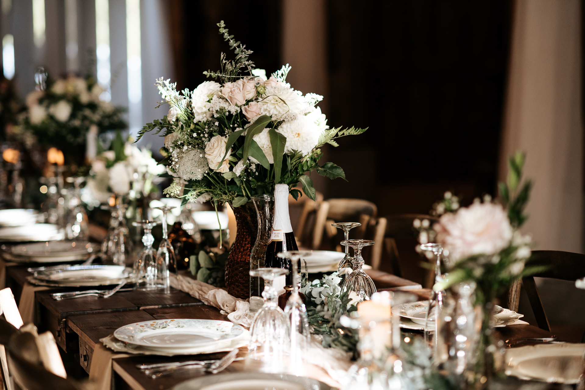 Floral arrangement on a reception farm house table with elegant table wear