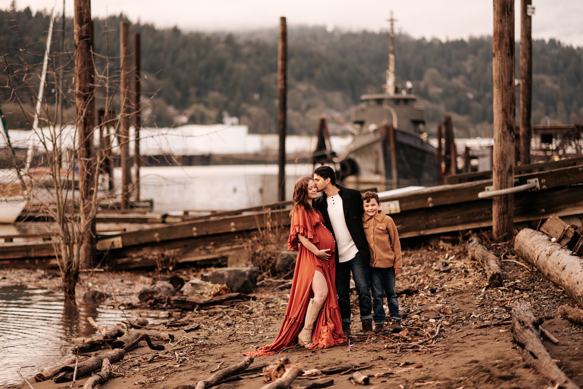 Pregnant woman with her family by a river wearing a red maternity dress