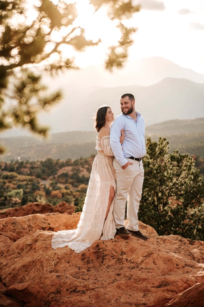 Couple standing on red rock formations for their engagement session at Garden of the Gods 