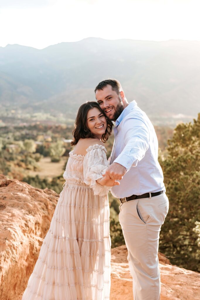 Couple holding hands at their Garden of the Gods engagement session with Pikes Peak in the Background