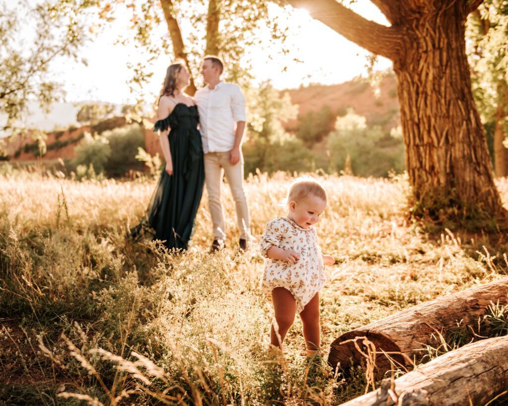 Baby girl walking in the grass exploring the outdoors wearing a off white romper and rust colored leggings